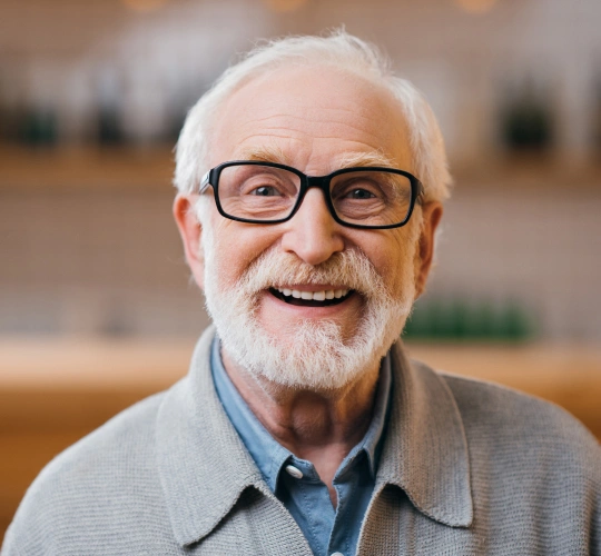 Smiling older man with white beard and glasses in professional office setting.